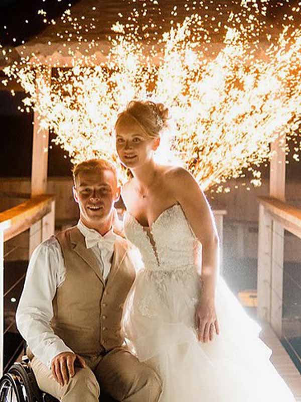 Wedding couple pose in front of a spark arch.